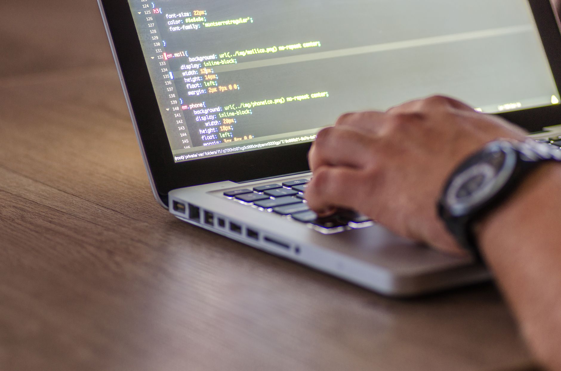Developer typing on a laptop with lines of code visible on the screen