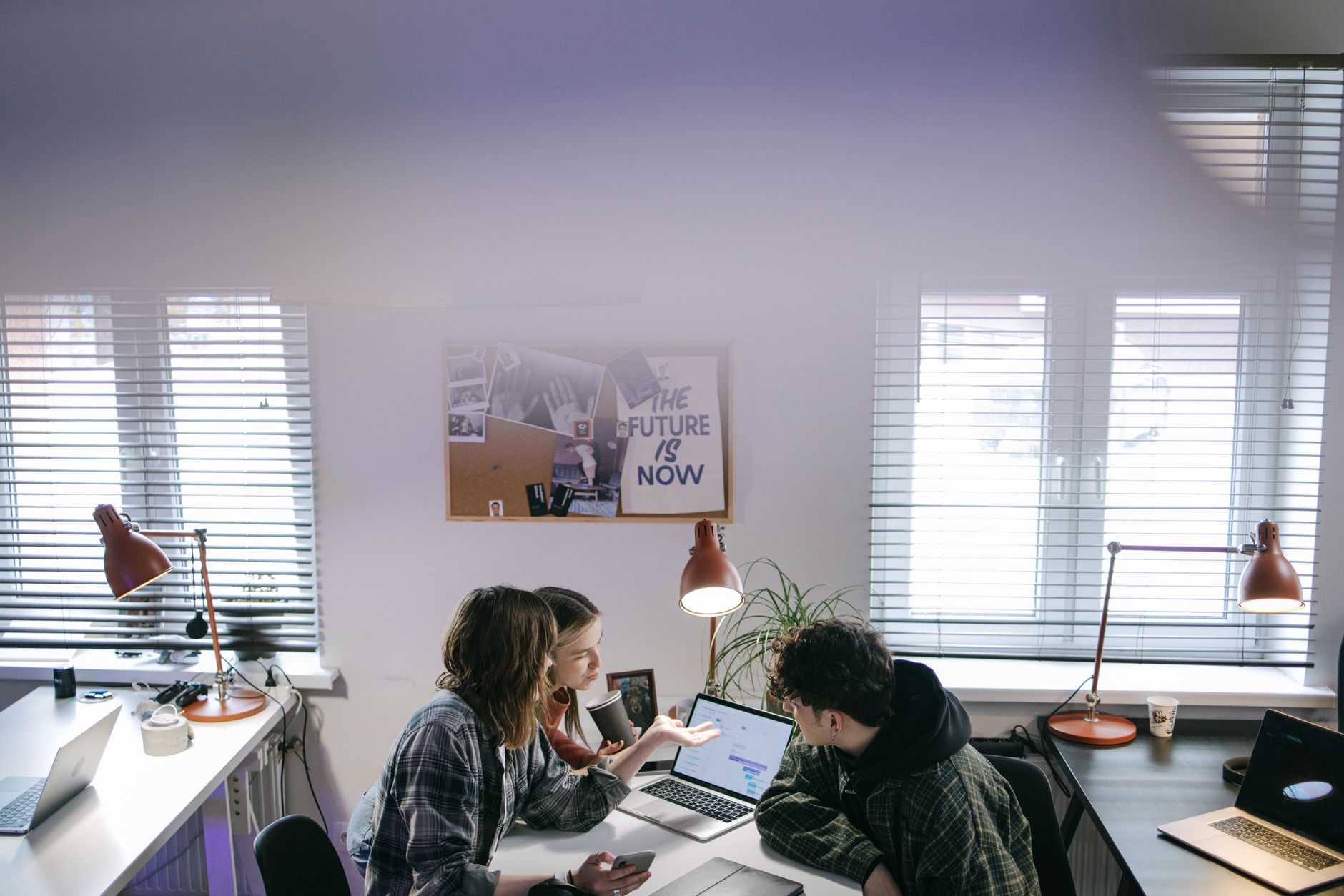 Small team of colleagues working together at laptops in a bright office